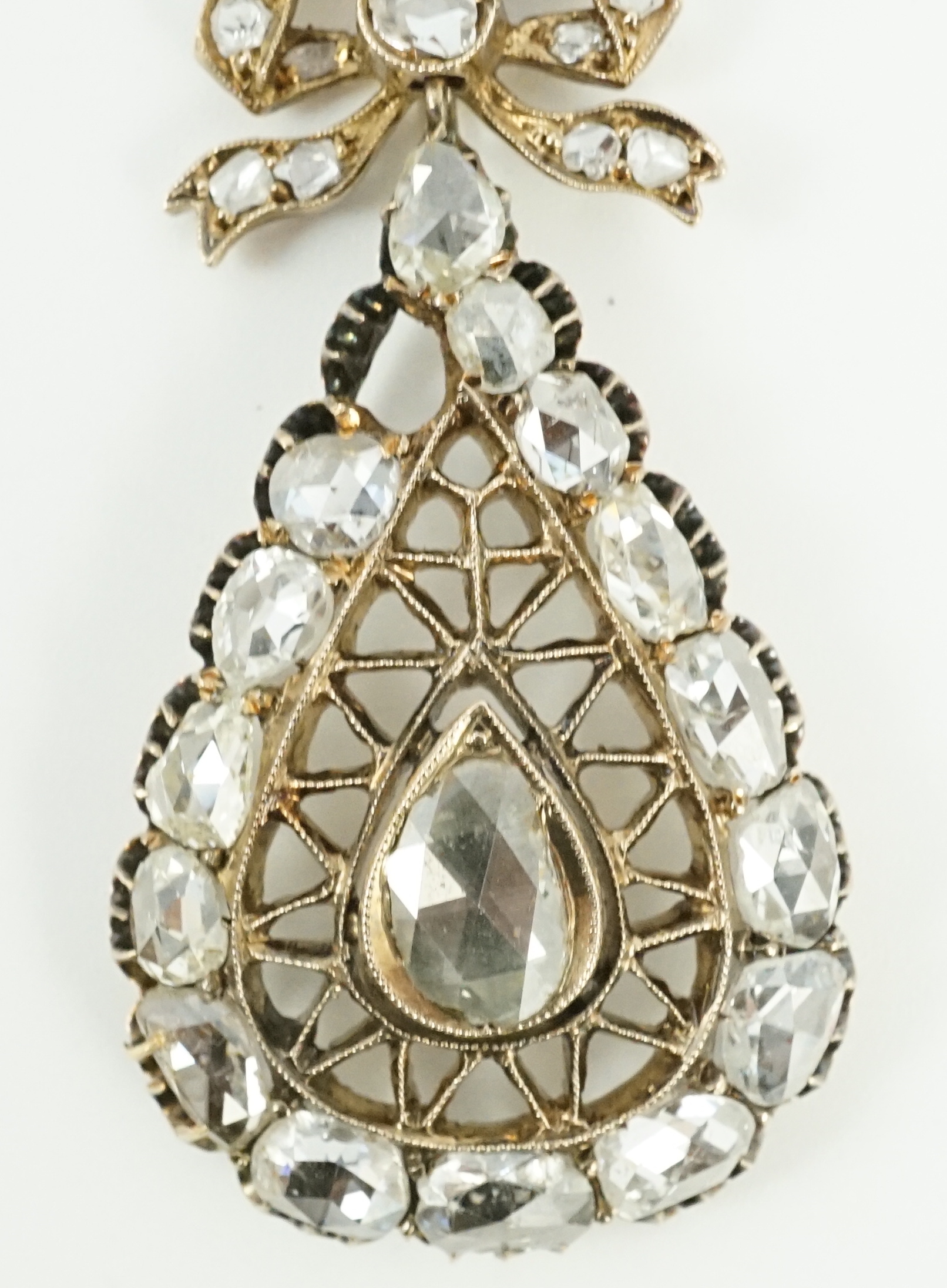 An early 19th century gold and rose cut diamond cluster set pear shaped drop pendant, with ribbon bow bale